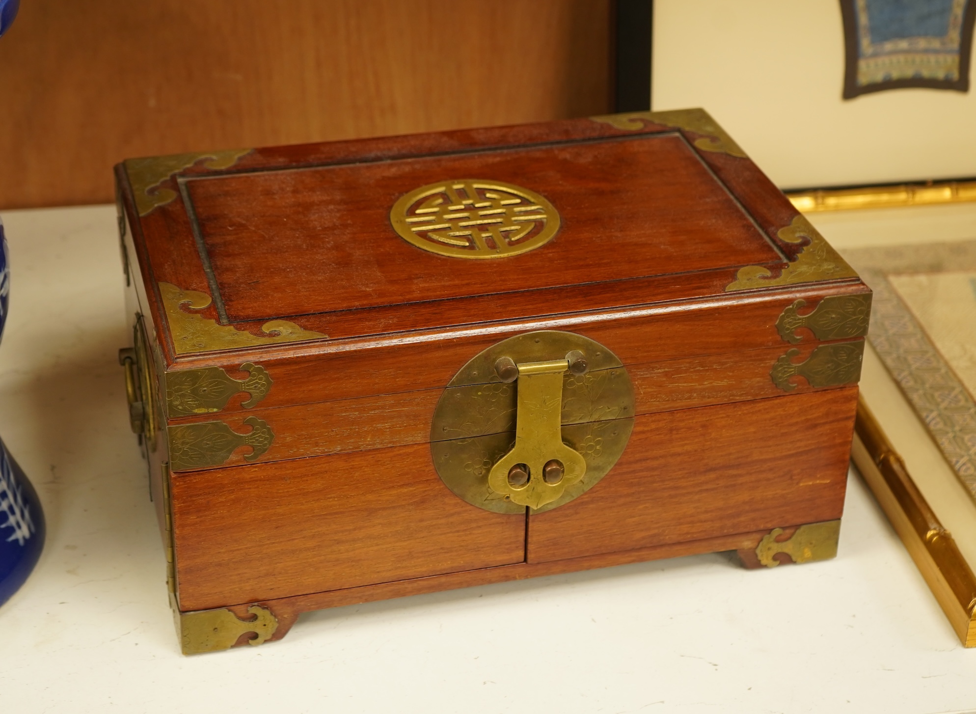A Chinese brass bound rosewood jewellery box with twin handles, the interior with sewing accessories and threads, 35cm wide